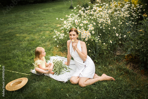 Obraz na płótnie mother plays with her daughter, relax, collect daisies w salonie