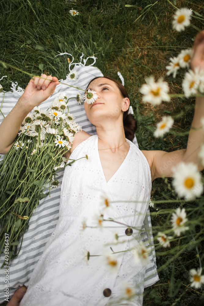 young woman lies in daisies