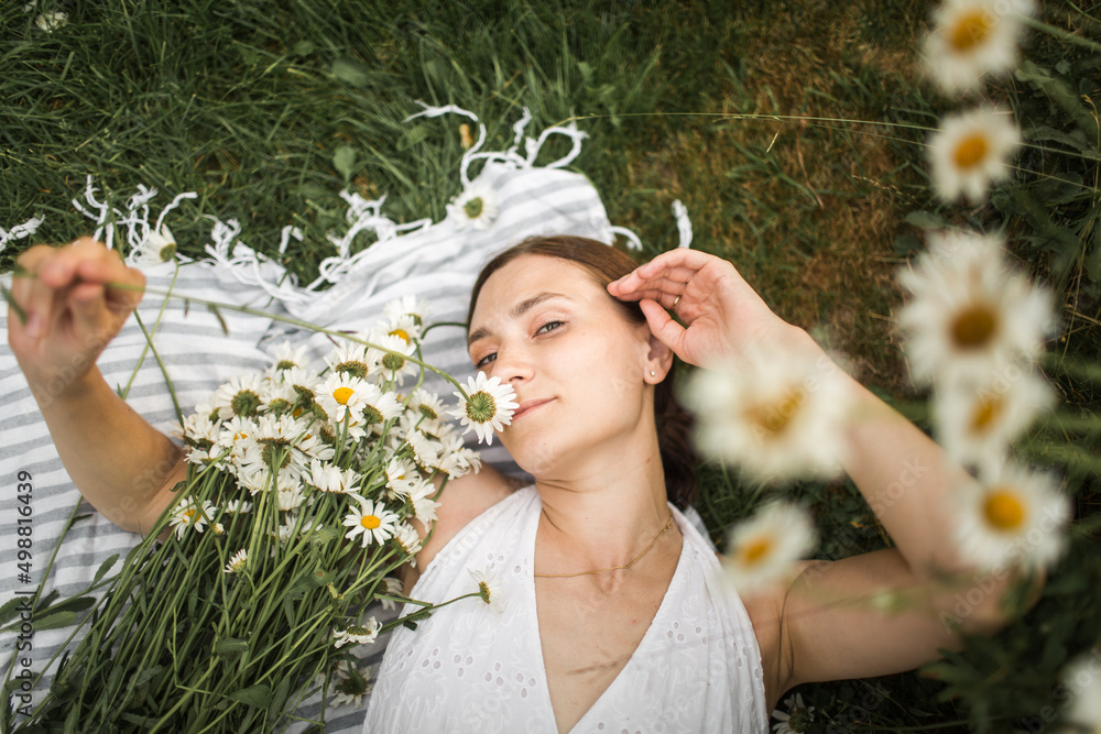 young woman lies in daisies