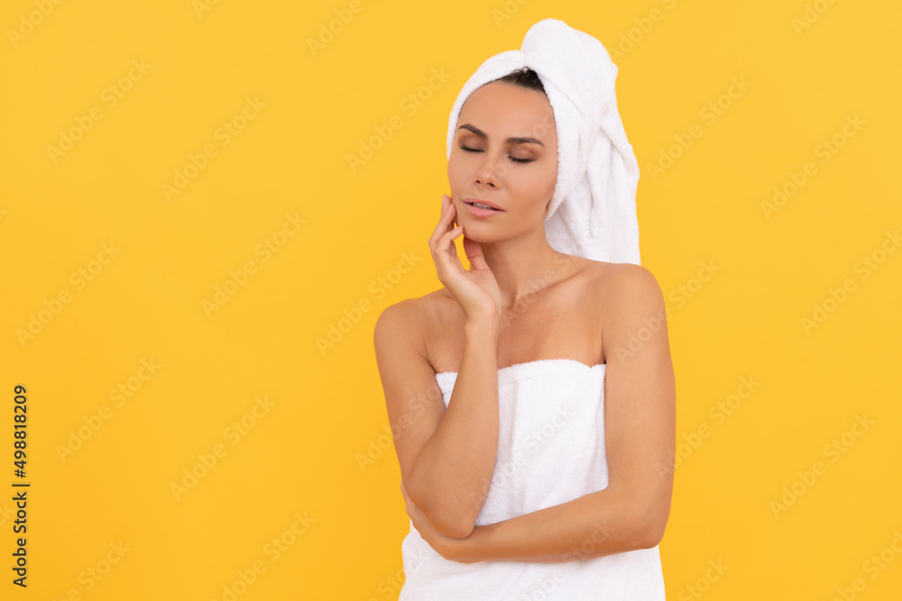 young woman in towel after shower on yellow background with copy space