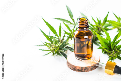 CBD oil in glass bottles and cannabis leaves at white table. Close up. Medicine and cosmetic product.