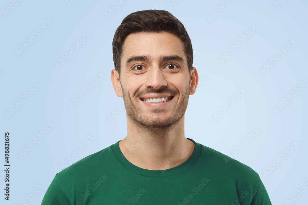Fototapeta premium Attractive optimistic smiling handsome man in green t-shirt looking at camera