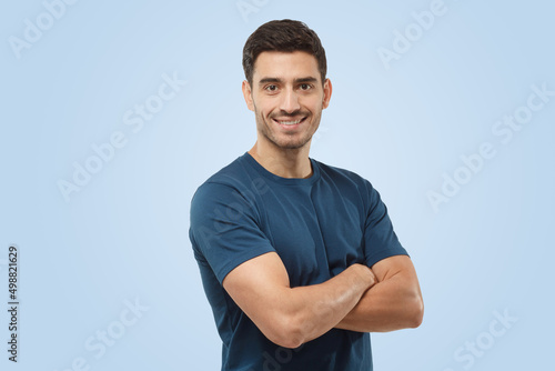 Athletic young sporty man in blue t-shirt standing with crossed arms