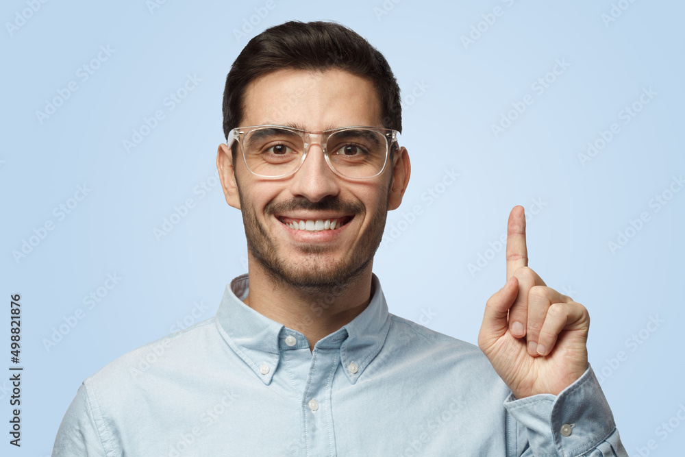 Attractive cheerful man in blue shirt points up with his finger Attractive cheerful man in blue shirt points up with his finger