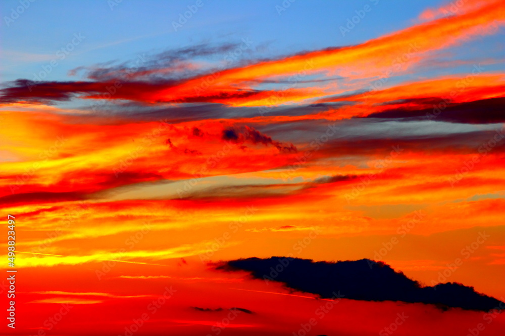 Breathtaking sunset of red, orange and yellow colours on the blue sky with weird clouds in Monte Vidon Corrado