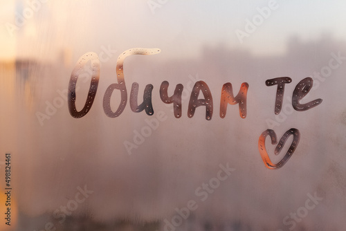 Lettering text in Bulgarian language words I love you in english and heart shape on sunset wet window photo