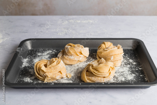 Rolled up nest of freash tagliatelle on a tray photo