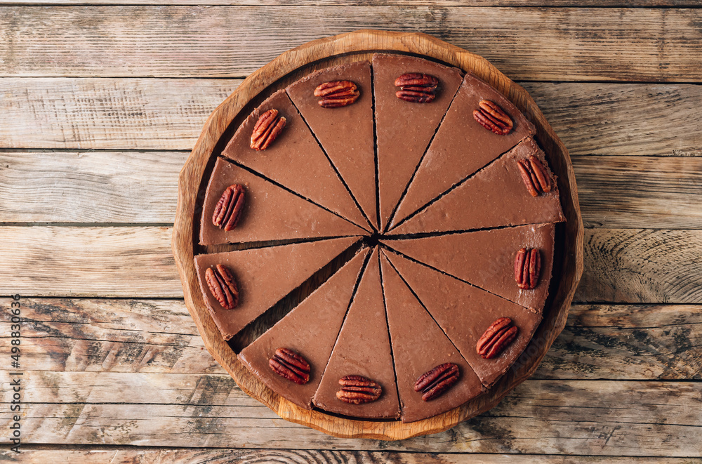 Chocolate cheesecake with pecans on rustic wooden background.