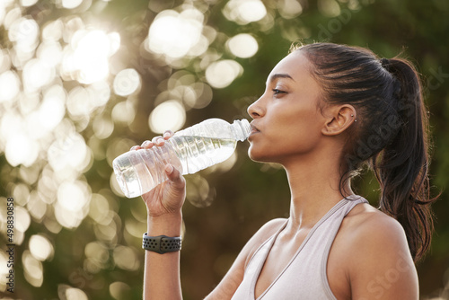 Take breaks when you need to replenish your energy. Shot of a sporty young woman drinking water while exercising outdoors.