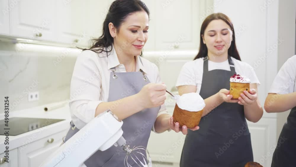 a mother and daughters decorate icing, dried berries and flowers easter cakes. a mother and daughters decorate icing, dried berries and flowers easter cakes.