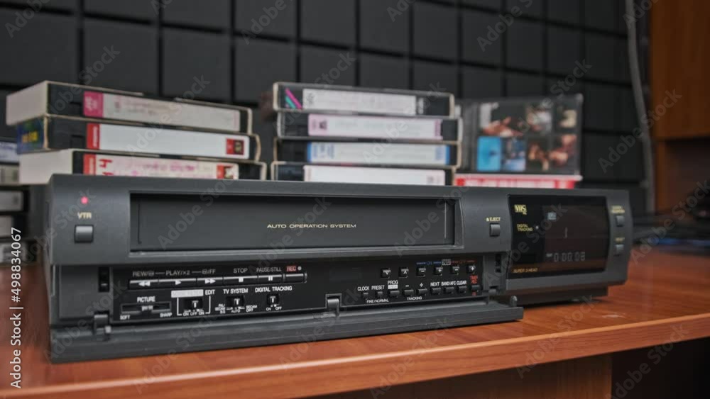 Eject VHS tape cassette from VCR player. Man pulls out VHS from vintage