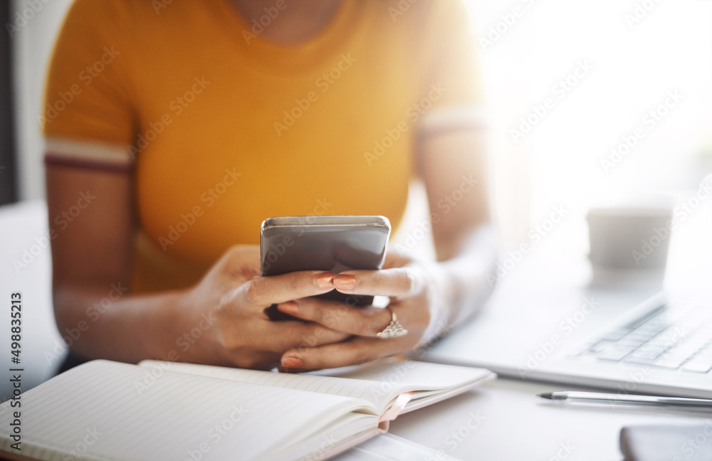 Staying connected is important at the office. Closeup shot of an unrecognizable female designer using a cellphone in her home office.