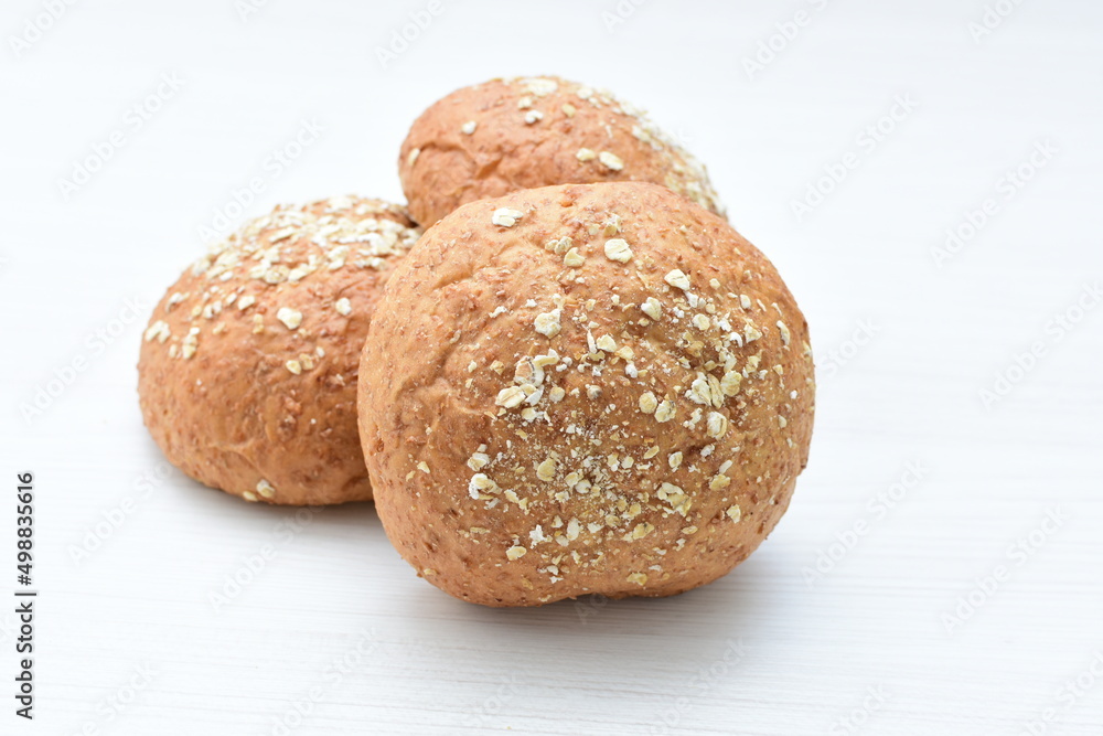 Round wholemeal oat bread, sweetened with natural panela, displayed on white wood Round wholemeal oat bread, sweetened with natural panela, displayed on white wood