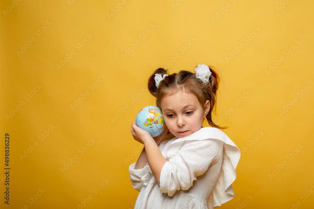 a cute six-year-old girl hugs a mock-up of the Earth a cute six-year-old girl hugs a mock-up of the Earth