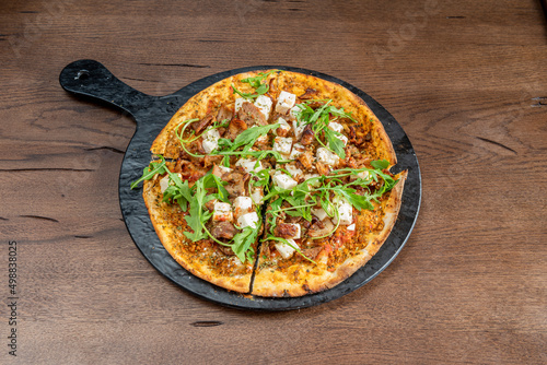 One-person sliced pizza with sliced meat, diced fresh cheese, tomato and arugula