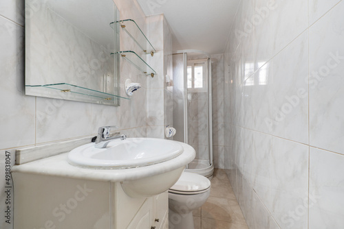 bathroom with white porcelain sink on marble countertop  square mirror without frame and quarter circle shower cabin