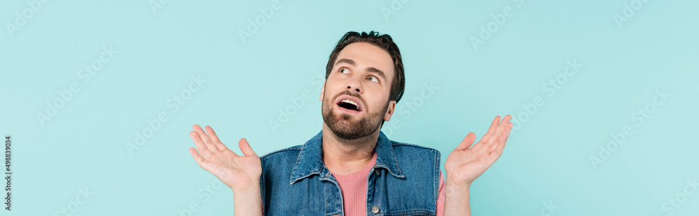 Young shocked man looking away isolated on blue, banner. Young shocked man looking away isolated on blue, banner.
