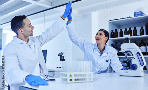 We did it. Cropped shot of two young scientists high fiving while working in their lab.