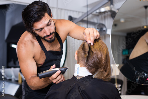 .Cheerful male professional shaving female's hair in hairdressing salon