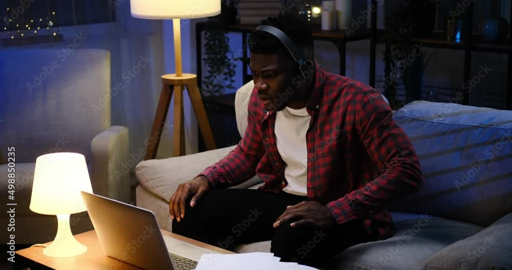 Frustrated African American businessman using laptop for video conference late night at home Frustrated African American businessman using laptop for video conference late night at home