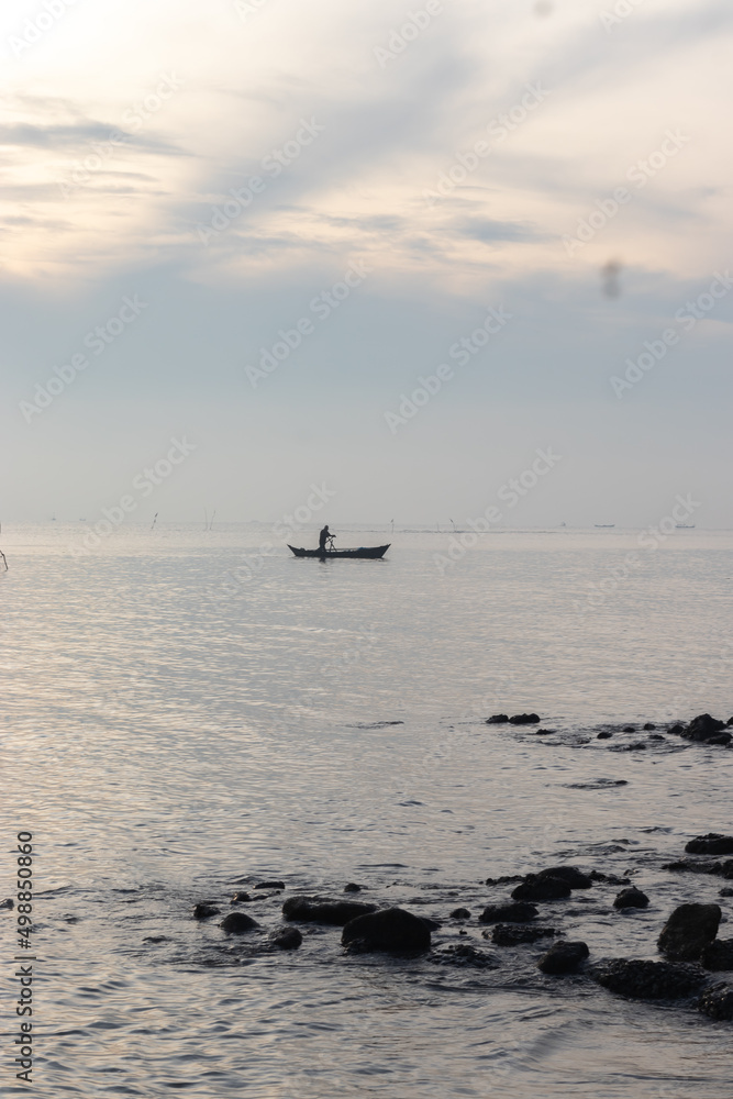 Silhouette of people with sea view and boats at sunrise in Medan, Indonesia, 2022