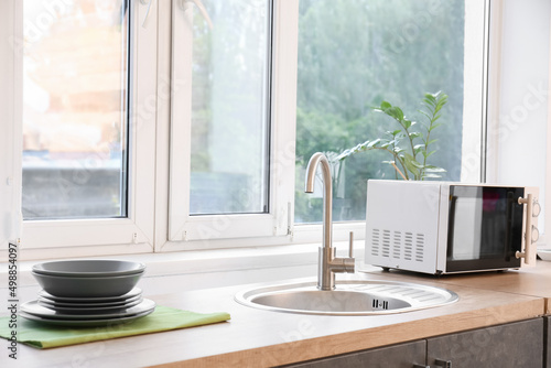 Wallpaper Mural Wooden counter with clean sink, dishes with microwave oven in interior of modern kitchen Torontodigital.ca