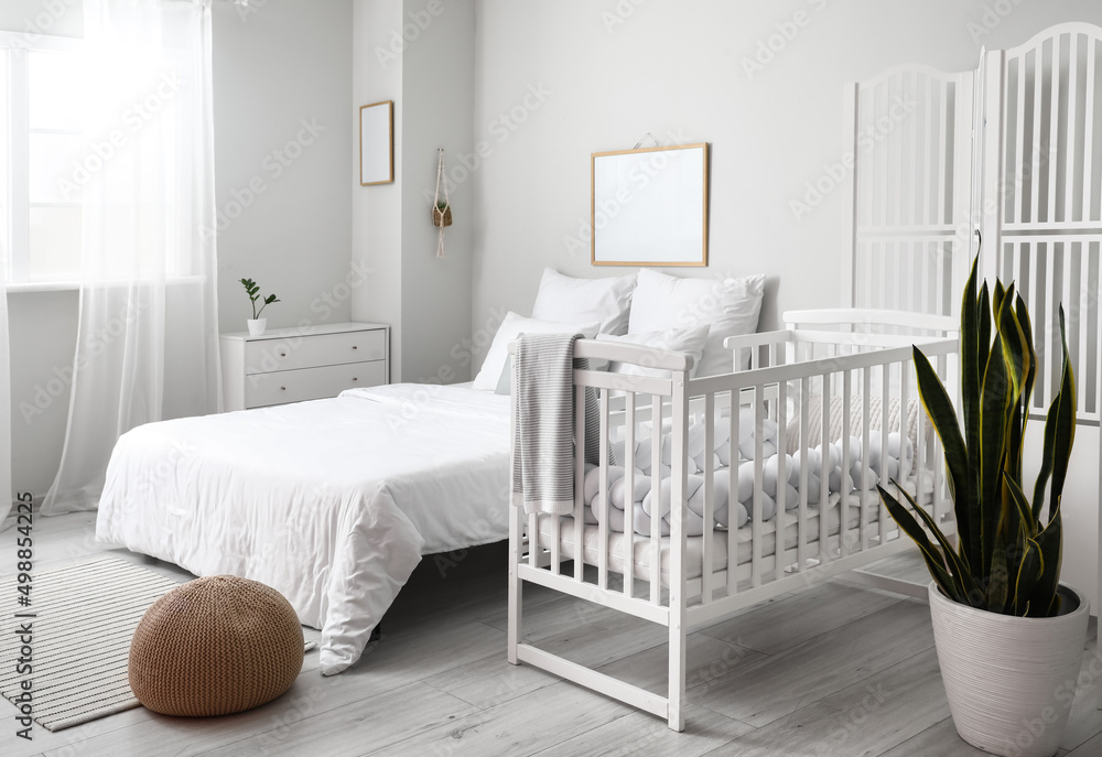 Modern interior of cozy room with big bed and comfortable baby crib Modern interior of cozy room with big bed and comfortable baby crib