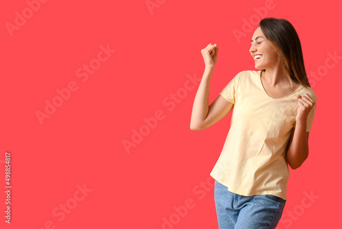 Happy young woman in blank t-shirt on color background