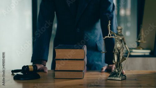 Lawyer Counsel Office work with contract documents and golden goddess scales with hammer on the table serve advice, justice and legal concept image with film grain effect.