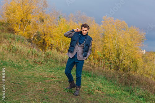 Tall handsome man walking outdoor in yellow autumn forest on the hill before storm