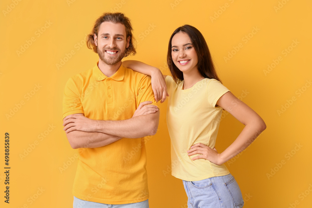 Young couple in stylish t-shirts on yellow background Young couple in stylish t-shirts on yellow background