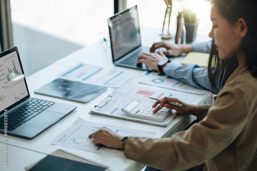 © Natee Meepian - businesswoman accountant hand working on calculator to calculate financial data report, accountancy document and laptop computer at office, business concept