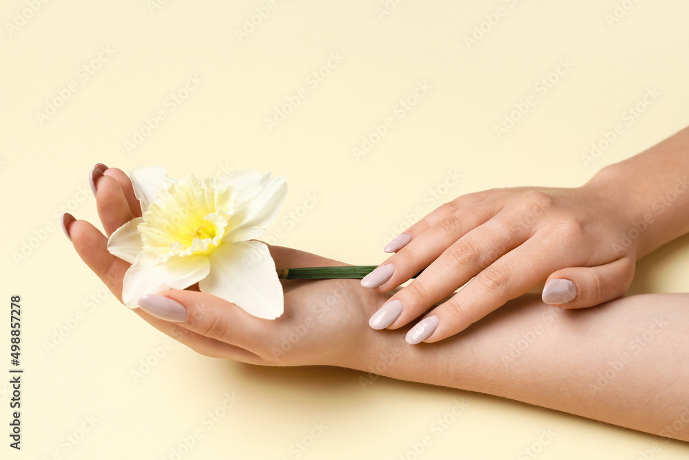 Woman with beautiful manicure and daffodil flower on yellow background