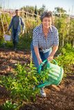 Portrait of smiling senior woman with watering can in garden