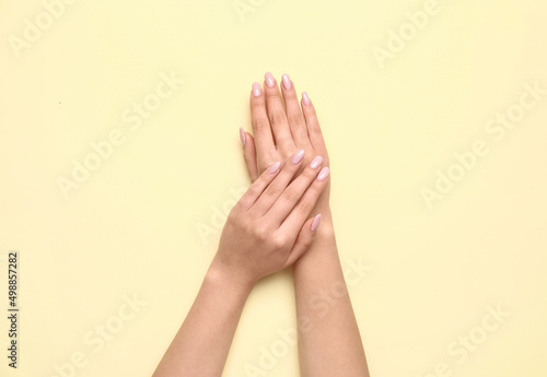 Female hands with beautiful manicure on yellow background