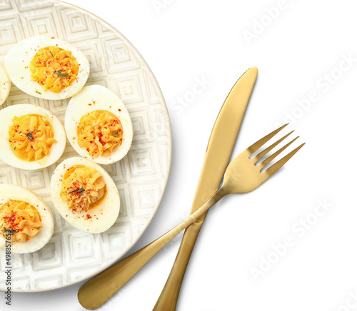 Plate with tasty stuffed eggs and cutlery on white background. Easter celebration