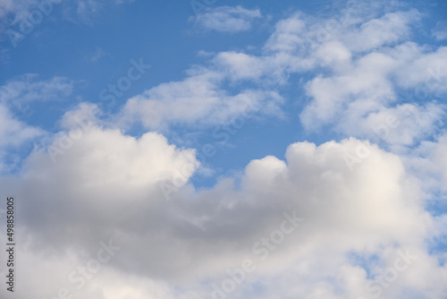 Cloudscape of puffy white clouds against a blue sky on a sunny day, as a nature background 