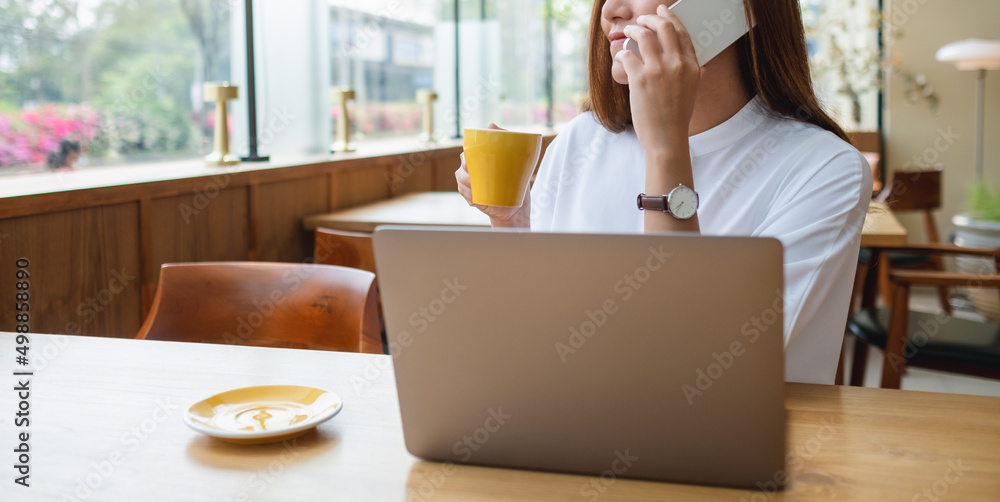 Closeup image of a businesswoman using and talking on mobile phone while working on laptop computer Closeup image of a businesswoman using and talking on mobile phone while working on laptop computer