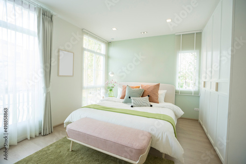 Modern bedroom with green and pink pillows on bed. Stylish bedroom interior design.