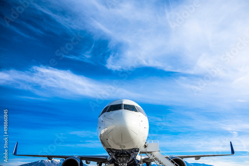 Photography Close up view of the front on an airplane sitting at the airport with clouds and sky in the background