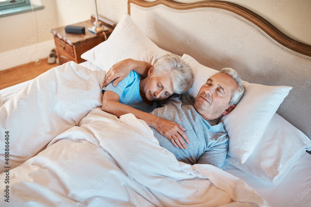 He still holds me until I fall asleep. Cropped shot of an affectionate senior couple cuddling each other while asleep in bed at a nursing home.