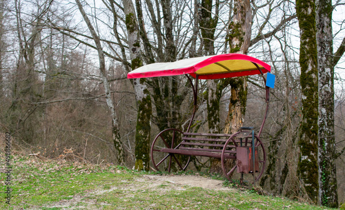 A bench in the forest in the off-season. Unusual design of a bench made of metal with a canopy.