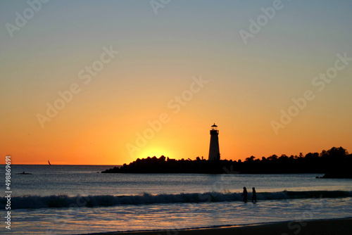 By the seaside at sunset with lighthouse, beach, wave, and people in Santa Cruz, California