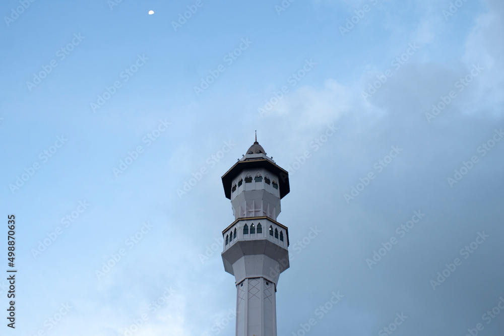 Mosque minaret and moon with clear sky