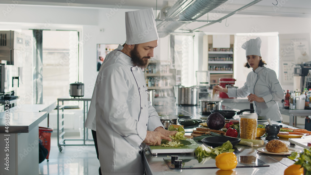 Authentic cook cutting coleslaw salad to make food recipe, using fresh ingredients in restaurant kitchen. Male chef using knife on cutting board to slice celery for gourmet dish. Authentic cook cutting coleslaw salad to make food recipe, using fresh ingredients in restaurant kitchen. Male chef using knife on cutting board to slice celery for gourmet dish.