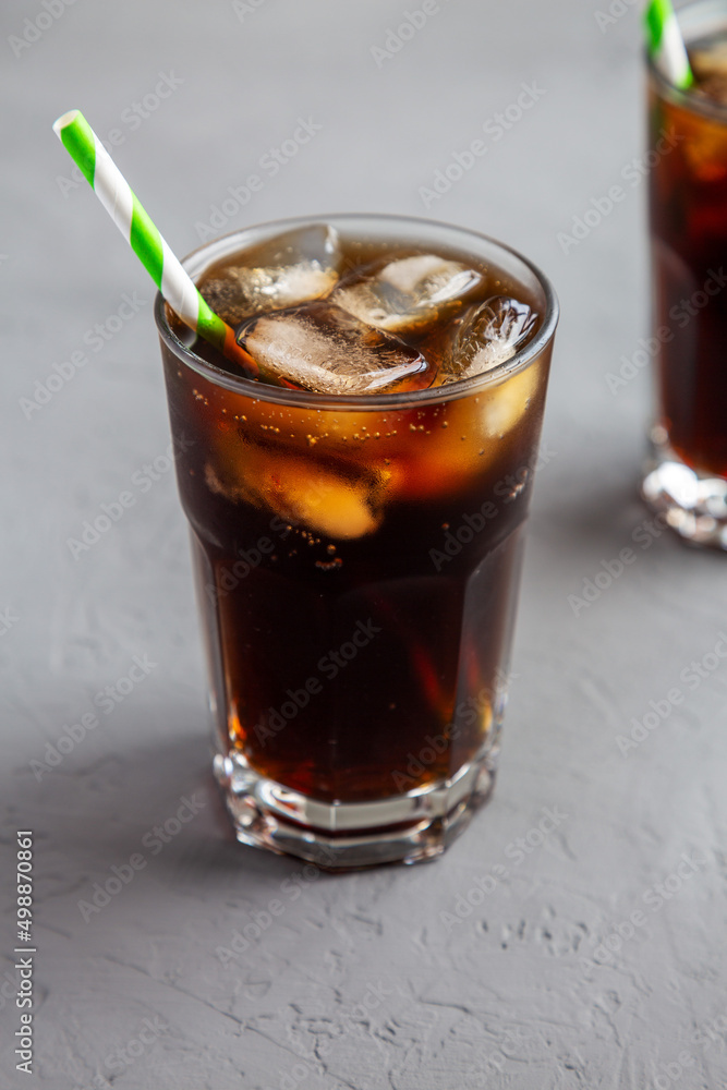 Cold Refreshing Dark Cola with Ice Cubes, Straws on a gray background, side view. Cold Refreshing Dark Cola with Ice Cubes, Straws on a gray background, side view.