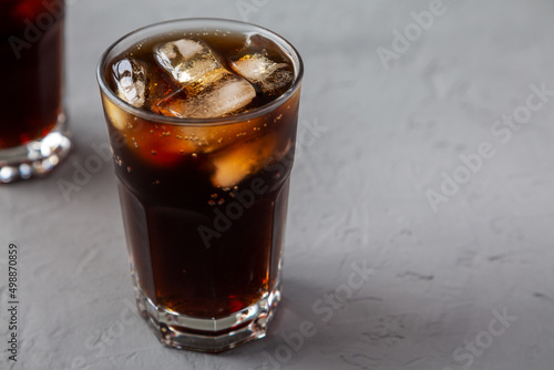 Cold Refreshing Dark Cola with Ice Cubes on a gray surface, low angle view. Space for text.