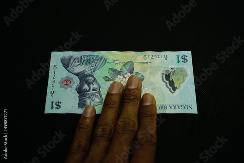 1 BND, one Brunei Darussalam Dollar money, was held by businessman, money concept isolated on black background photo