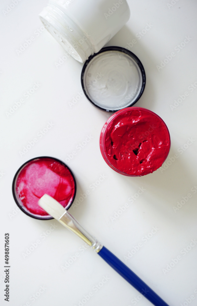 Red and white opened paint bottle with a paint brush lying on the side against white background Red and white opened paint bottle with a paint brush lying on the side against white background