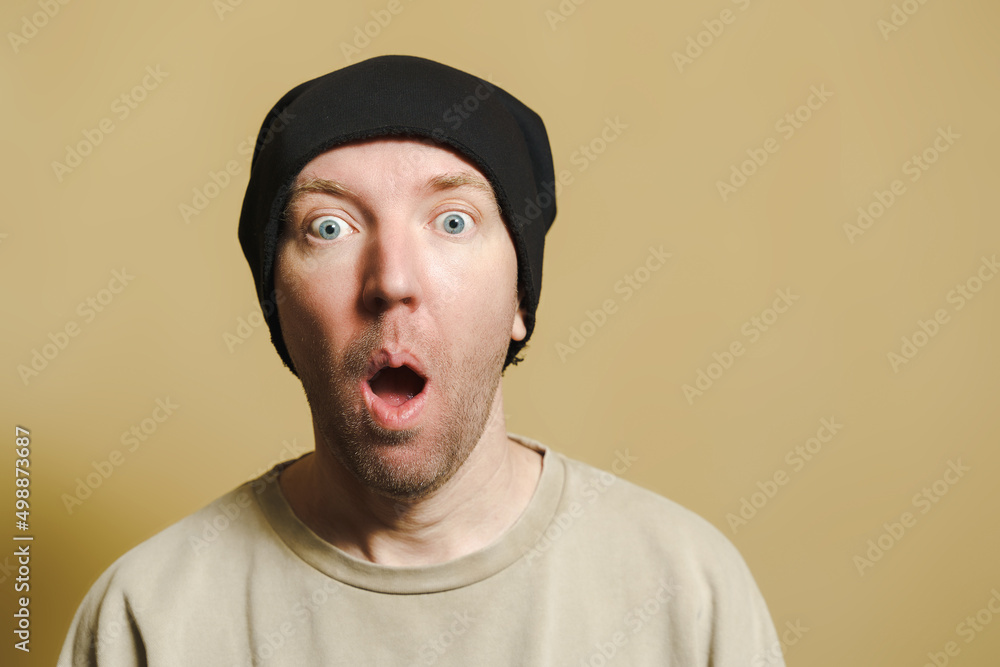 A man in a black cap looks with fear. Portrait of a young man making faces A man in a black cap looks with fear. Portrait of a young man making faces